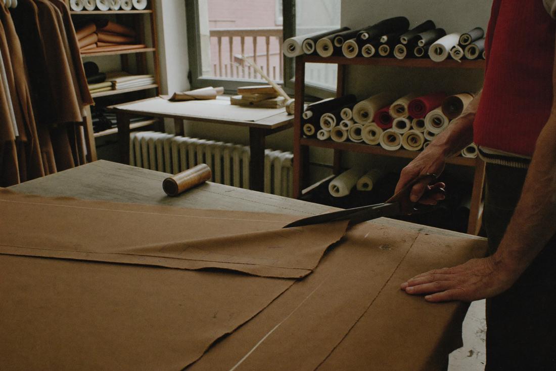 Tailor cutting camel wool fabric in the atelier