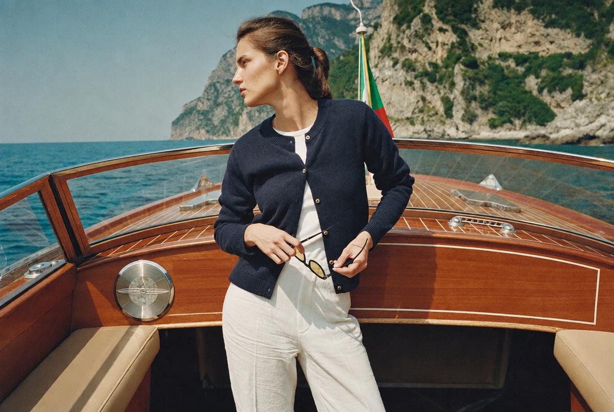 Model in a navy cardigan on a wooden boat off the Amalfi coast